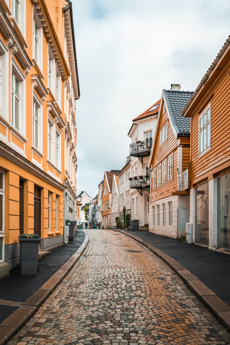 Narrow cobblestone street lined with colourful wooden houses in Bergen, Norway Narrow cobblestone street lined with colourful wooden houses in Bergen, Norway